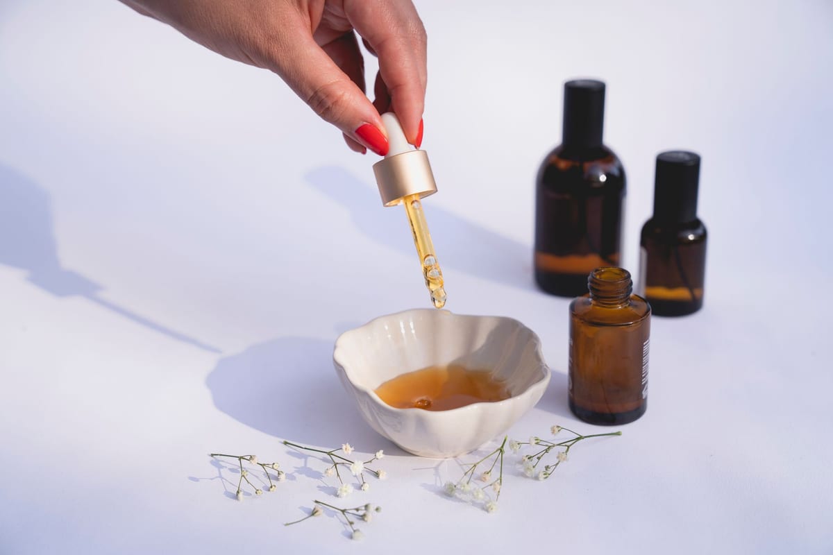 Amber skincare bottles and a dropper of serum on a white table